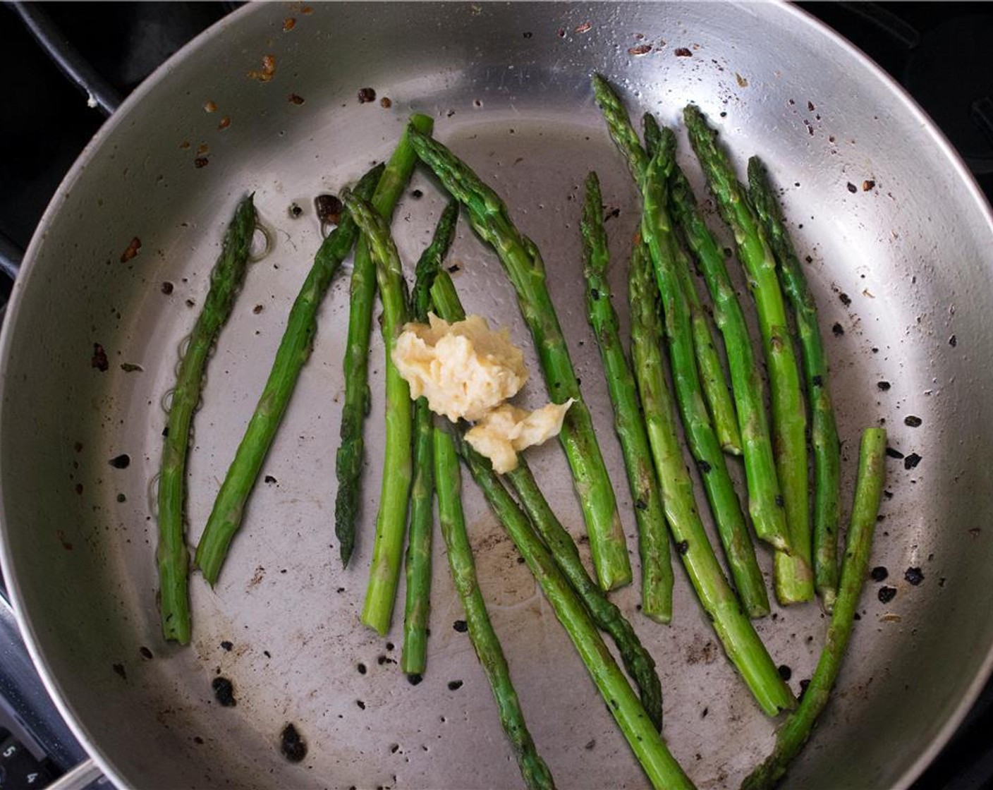 step 7 In a large skillet over medium-high heat, heat 1 tbsp of olive oil. Add asparagus to the skillet. Cook for 2 minutes, turning occasionally. Add 1 tbsp of the roasted garlic miso butter. cook the asparagus for another minute, until tender.