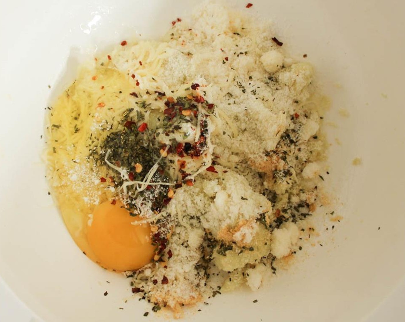 step 6 Place the cauliflower pulp in a mixing bowl and add the Parmesan Cheese (4 Tbsp), Shredded Part-Skim Mozzarella Cheese (4 Tbsp), Dried Oregano (1/2 tsp), Dried Basil (1/2 tsp), Crushed Red Pepper Flakes (1/4 tsp), Salt (1/4 tsp), Garlic Powder (1/2 tsp) and Egg (1).
