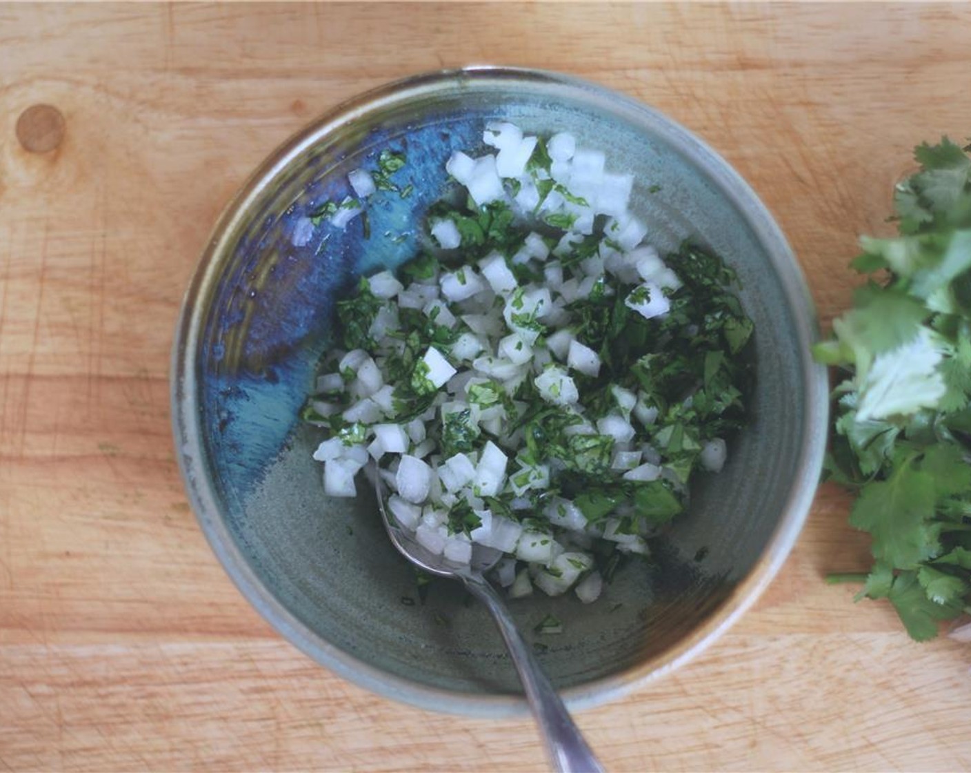 step 5 Meanwhile, make a quick topping by mixing the Yellow Onion (1/2) and Fresh Cilantro (4 Tbsp) with juice from Lemon (1) and a little salt.