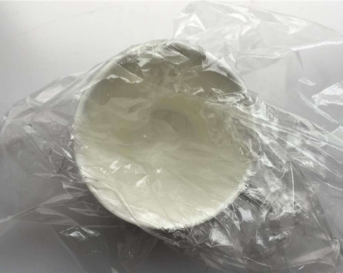 step 2 Choose a small cup or ramekin. Gently place the cling film in it and carefully shape it against the inside of the ramekin or using your fingers.