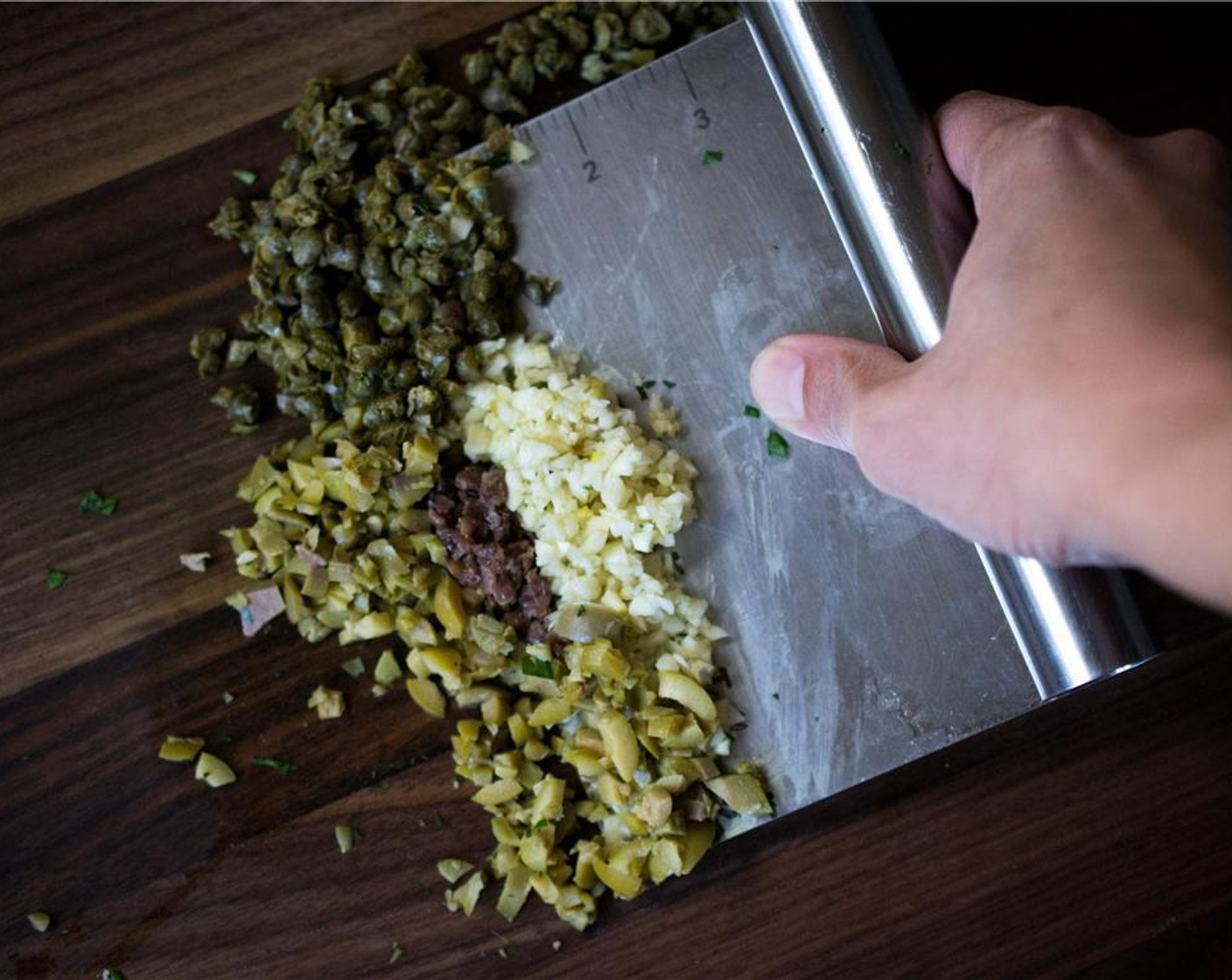 step 2 Add in Anchovy Fillets (3), Capers (1 1/3 Tbsp), Green Olives (3), Garlic (4 cloves) into the bowl of greens.