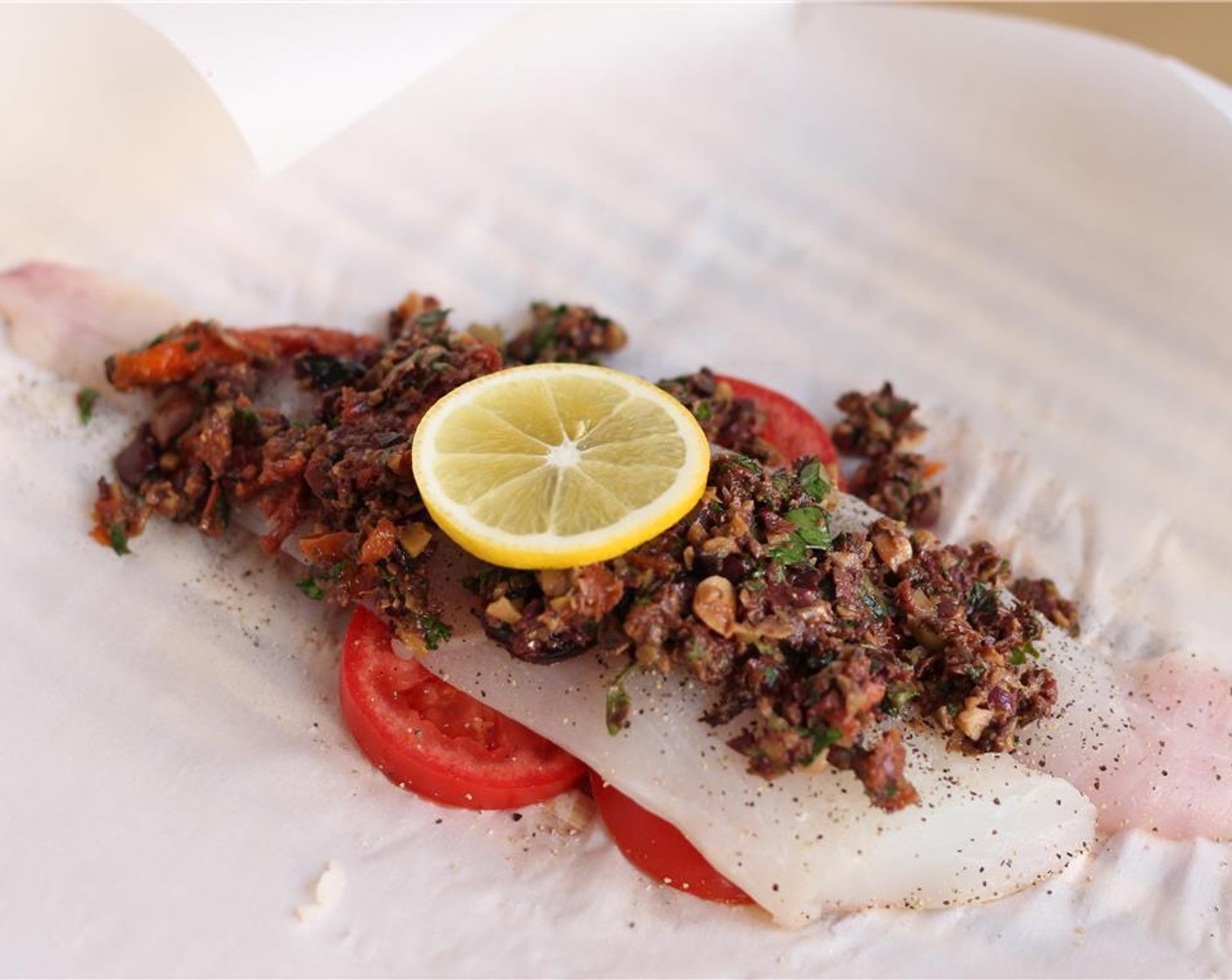 step 6 Spread 1/4 cup of the tapenade on top of the cod. Top with a slice of lemon. Drizze 2 Tbsp of the Chardonnay (4 Tbsp) below the fish. Repeat this process with the second cod fillet.