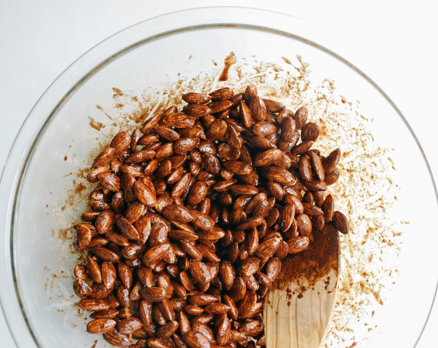 step 2 In a large mixing bowl, add Raw Almonds (3 cups), Pure Maple Syrup (4 Tbsp), Vanilla Extract (2 tsp), Unsweetened Cocoa Powder (1 tsp), Ground Cinnamon (1 tsp), Ground Cardamom (1 tsp), Ground Ginger (1 tsp), Ground Cloves (1/2 tsp), and Ground Black Pepper (1/4 tsp). Mix to coat well.