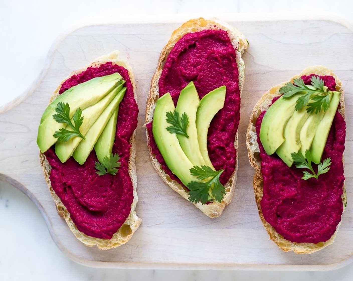 step 7 Spoon hummus into a serving dish, drizzle with a bit of Olive Oil and top off with Fresh Cilantro (to taste) or parsley. I served my spread on toast with some avocado!