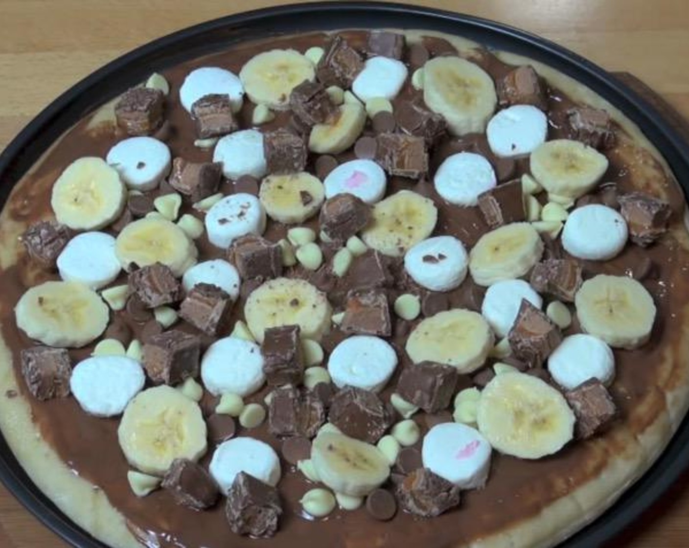 step 2 Cover pizza base with Nutella® (4 Tbsp). Top with Marshmallows (to taste), Milk Chocolate Chips (1 handful), White Chocolate Chips (1 handful), Banana (1) and Mars® Bars (2).
