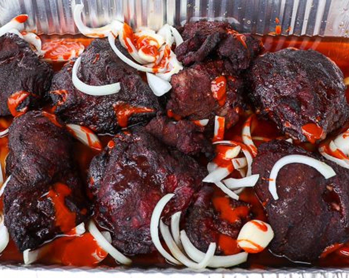 step 4 Remove beef cheeks from out and place in aluminum pan. Add Onion (1), Garlic (10 cloves), Beef Stock (3 cups) and Mexican Style Hot Sauce (4 Tbsp).