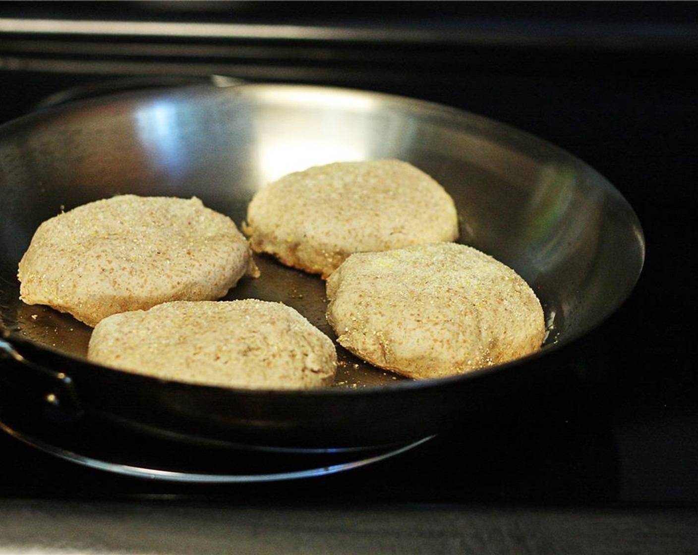 step 9 Heat a large frying pan or cast iron skillet over medium heat. When hot, scoop about a tbsp of shortening into the pan and tilt it so it melts evenly over the pan. Carefully place muffins cornmeal-side down, and cook for 8 minutes on low.