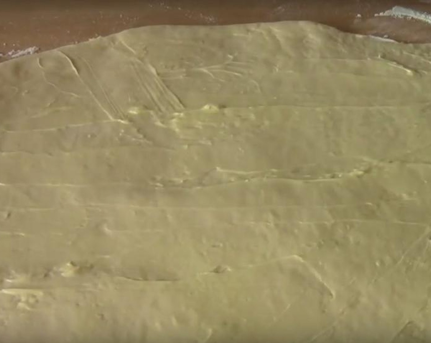 step 5 Once the dough has doubled in size, take it out of the bowl, punch it in the middle, and knead it it for a few minutes. Roll it out for about 40 centimeters and 30 centimeters into a big rectangle. With a spatula, spread the softened Butter (3.5 oz) it. Sprinkle the cinnamon mixture all over.