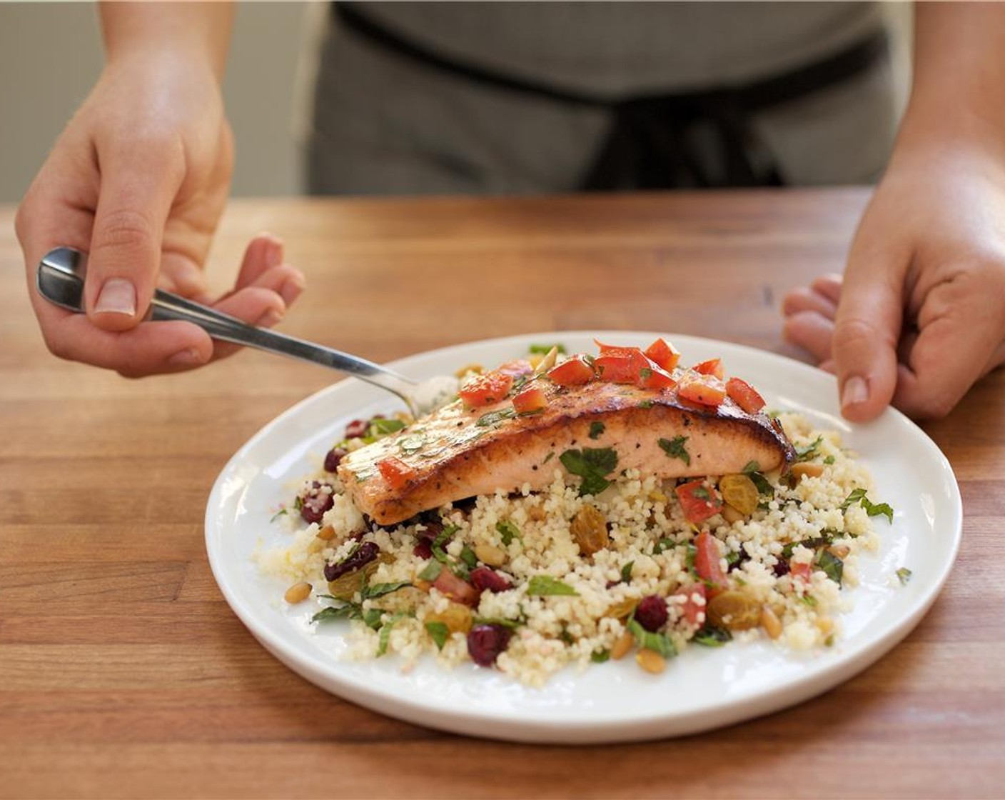 step 15 Divide the couscous between two plates. Lay a piece of salmon over the couscous. Top the fish with the tomato and cilantro mixture.