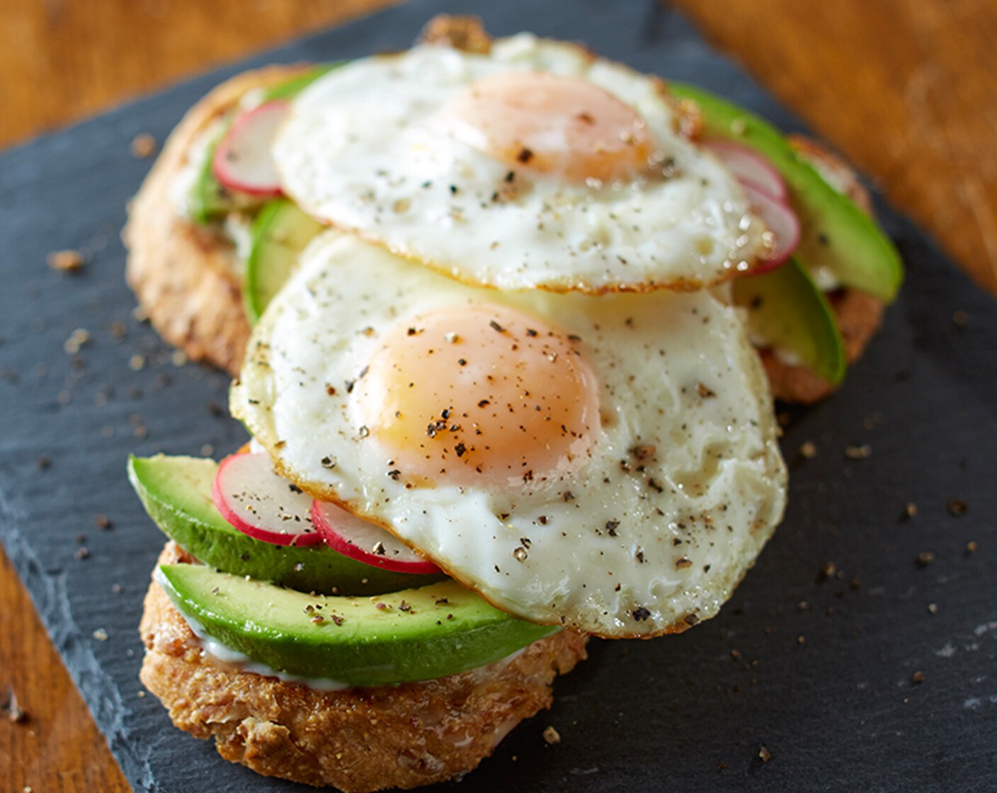 step 3 While eggs are cooking, lightly toast Multigrain Bread (2 slices). Spread with remaining Buttery Spread (2 tsp) and top with sliced Avocado (1/2) and Radishes (to taste), as desired. Place fried eggs on top. Sprinkle with Ground Black Pepper (to taste).