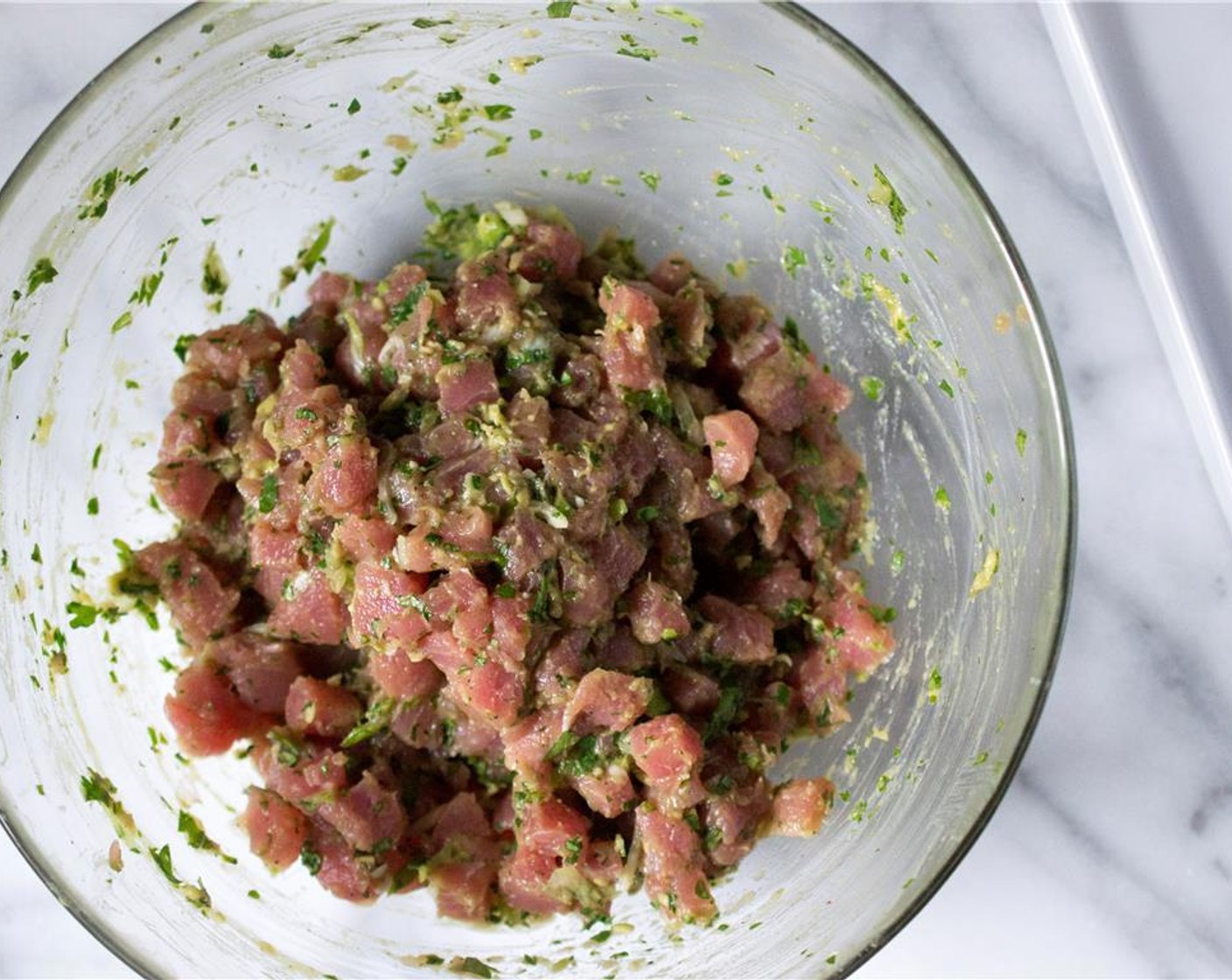 step 2 Add the Scallion (1 bunch), Fresh Cilantro (2 Tbsp), Fresh Ginger (1 tsp), Red Bird's Eye Chili Pepper (1), Avocado (1/2), Kosher Salt (1/2 tsp), and Ground Black Pepper (1/4 tsp) to the tuna. Gently work with your hands to incorporate all of the ingredients.