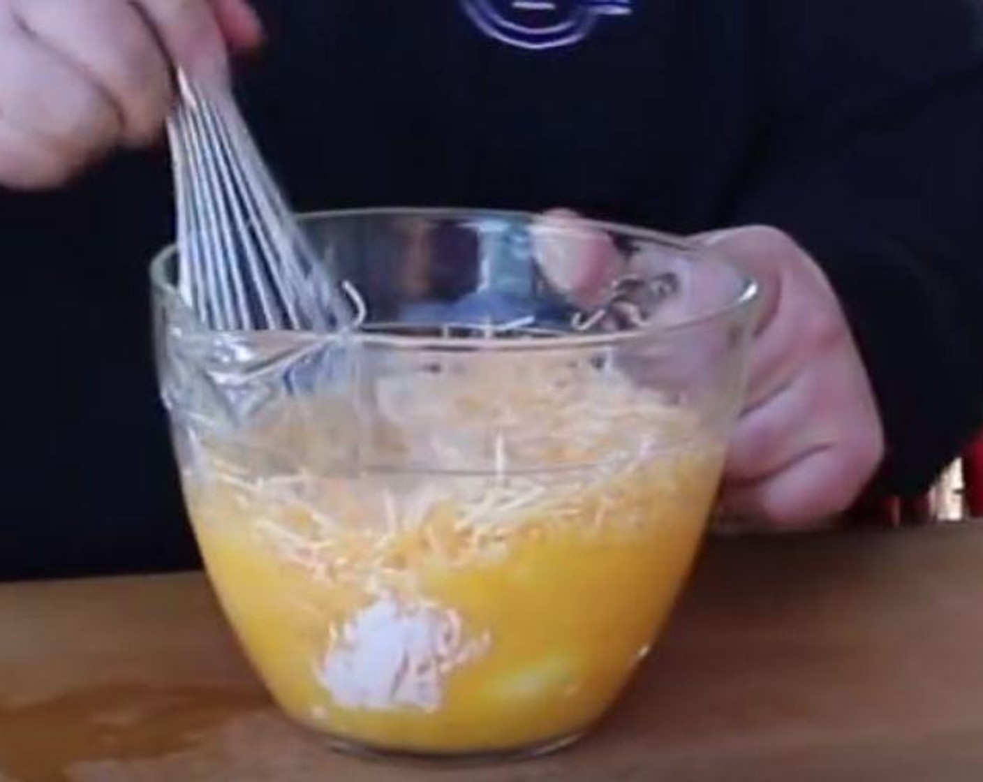 step 4 In a large mixing bowl, crack Large Eggs (10) and whisk. Add Shredded Cheese (2 cups), Sour Cream (1 cup), Hot Sauce (1 Tbsp) and a pinch of Salt (to taste) and Ground Black Pepper (to taste). Whisk to combine.