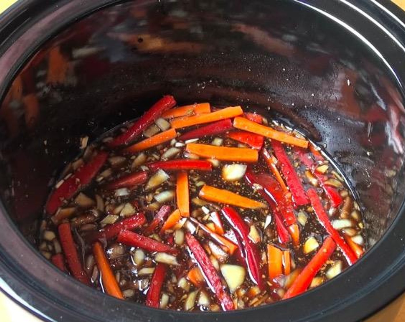 step 1 In a slow cooker, add Garlic (2 cloves), Fresh Ginger (2 tsp), Yellow Onion (1), Carrot (1), Red Bell Pepper (1), Brown Sugar (1 cup), Sweet Chili Sauce (4 Tbsp), Dark Soy Sauce (1/2 cup) and Water (1 cup). Stir together. Put the lid on and cook on high for 1 hour.