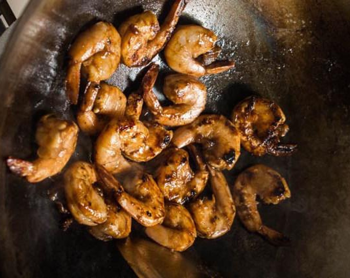 step 3 Heat Cooking Oil (2 Tbsp) in a wok over medium-high heat. Just as the wok starts to smoke a little, add the shrimp to the wok in one single layer. Leave the shrimp untouched for about 30 seconds to allow the shrimp to char slightly, then use a wok spatula to flip the shrimp to cook the other side. Stir-fry to ensure even cooking.