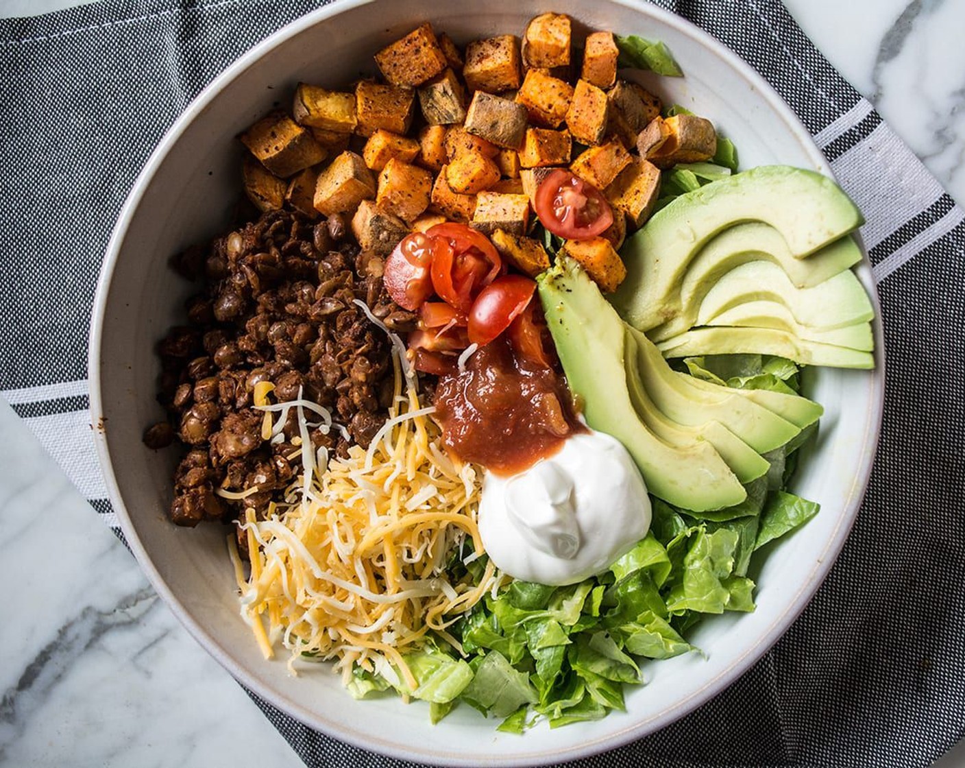 step 7 Begin by adding a layer of lettuce to the bottom of each bowl, then add half roasted sweet potatoes, half seasoned lentils, and top with your choice of Salsa (to taste), Shredded Cheese (4 Tbsp), Sour Cream (to taste), Avocado (1), and Cherry Tomato (1/2 cup).