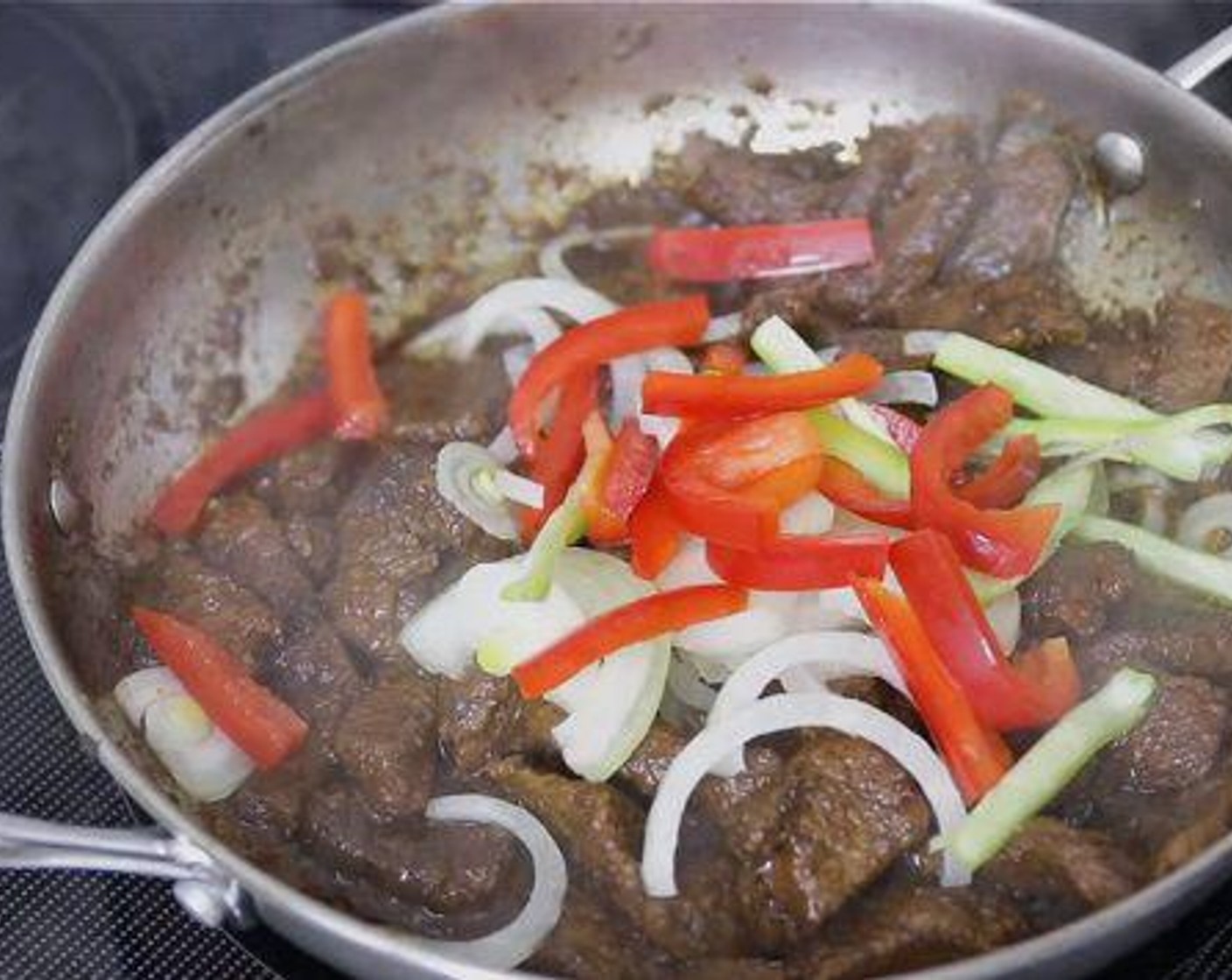 step 11 Once the beef is tender, add onion, cubanelle pepper and red bell pepper and stir to combine. Add Tomato Paste (4 Tbsp) and enough water to make a stew-like gravy consistency, then stir to blend everything well. Cover and cook for 3-5 minutes.