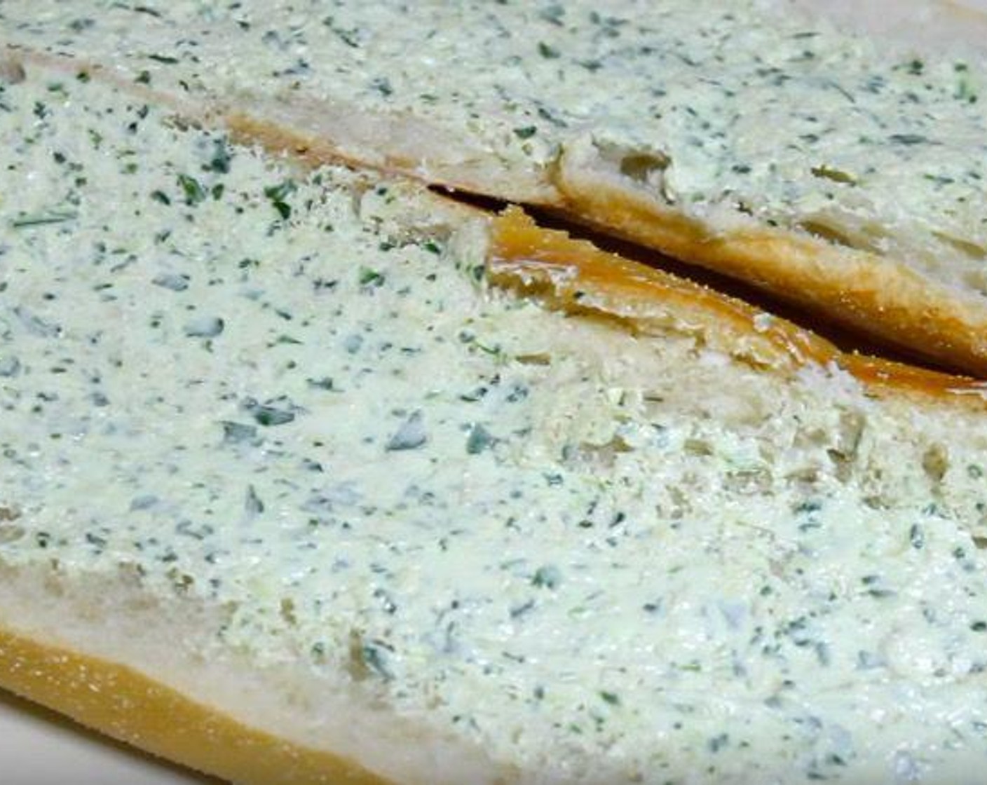 step 2 Cut Italian Bread (10 oz) in half lengthwise. Spread each side with the processed mixture and then bring the two halves back together. Wrap the bread in aluminum foil and transfer to a baking tray.