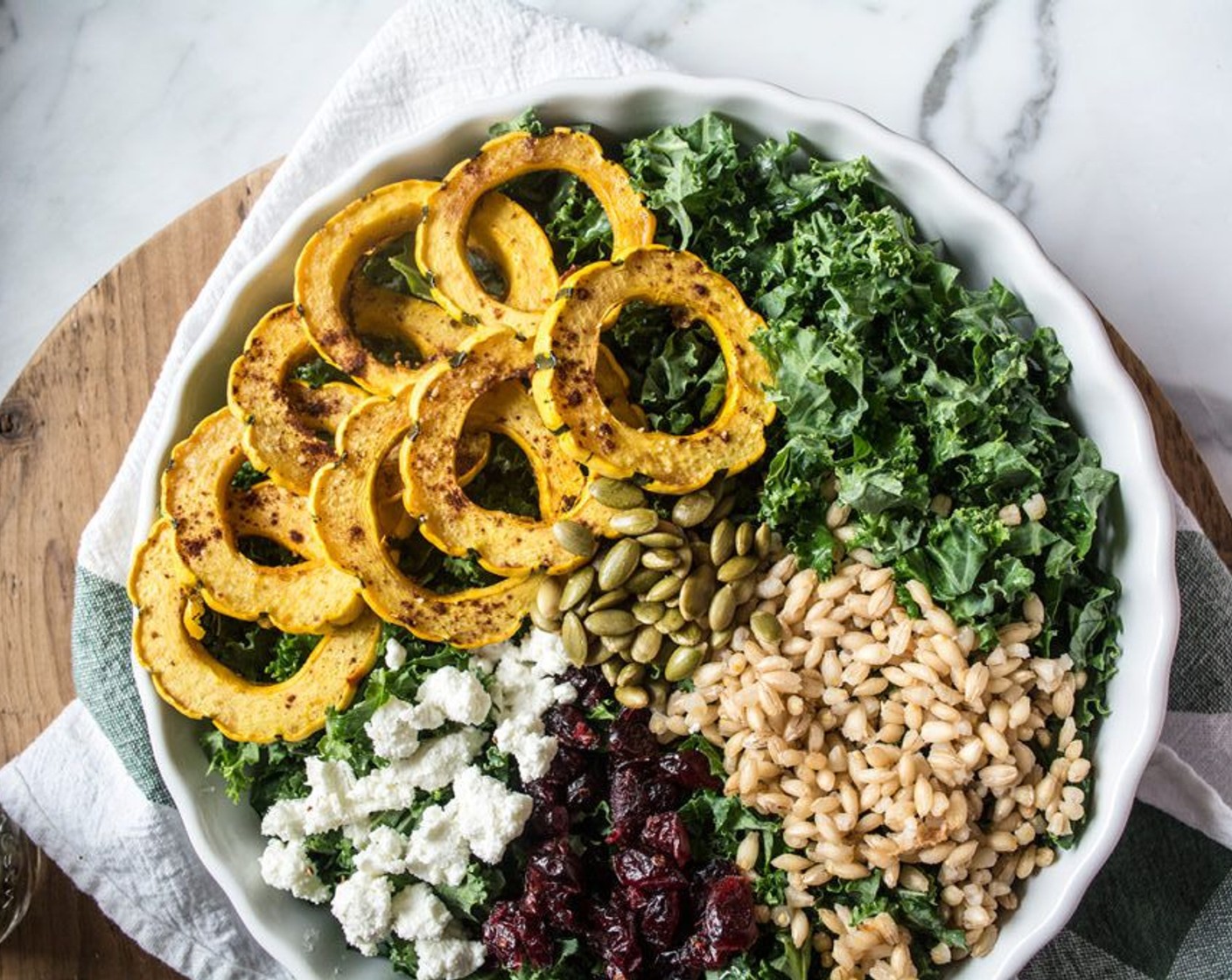 step 7 To assemble the salad, divide Kale (5 cups) between two large bowls or plates, then top each with roasted delicata squash, barley, Goat Cheese (2 2/3 Tbsp), Dried Cranberries (4 Tbsp) and Pepitas (2 Tbsp).