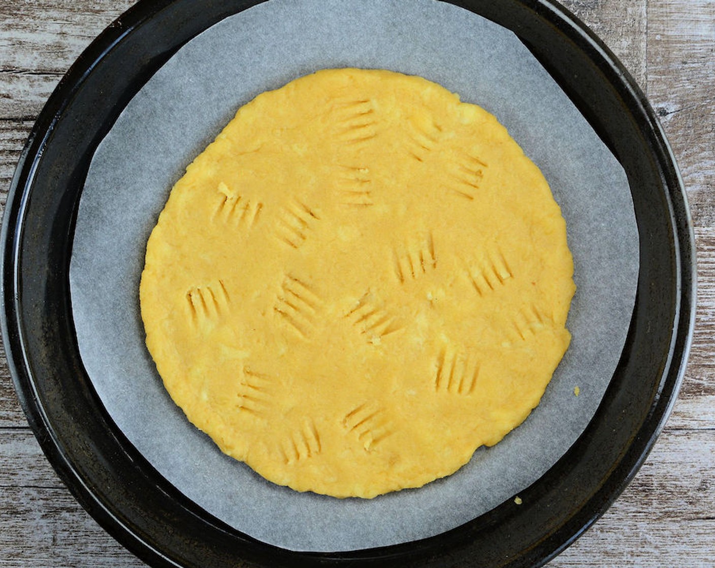 step 6 Transfer the crust to the pizza pan using the bottom piece of parchment paper. Using a fork or a toothpick, poke holes in the crust to prevent it from bubbling. Sprinkle with Garlic Powder (to taste) and Onion Powder (to taste).